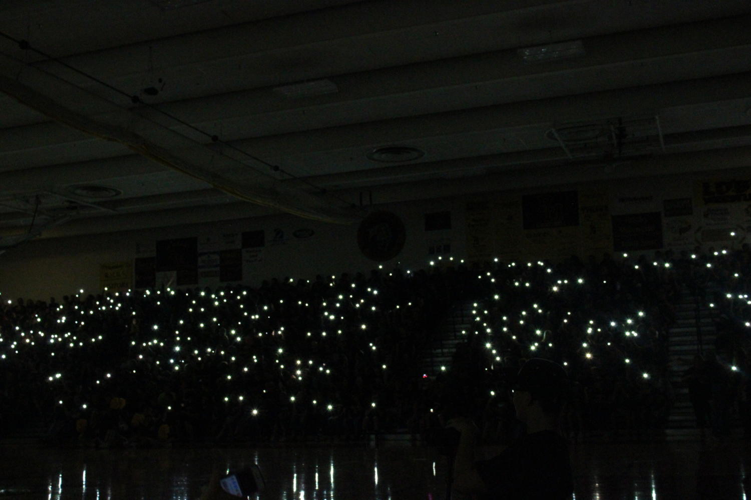 Rocky students shining their flashlights in the dark at the back to school assembly.