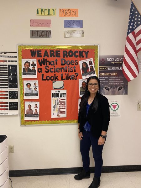 Dr. T. stands next to her What Does a Scientist Look Like poster in her classroom.