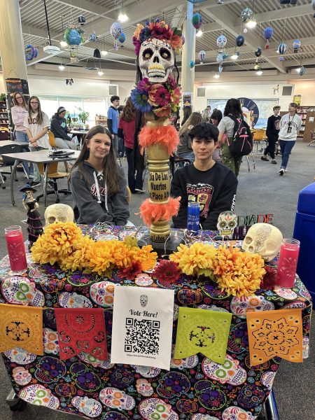 Seniors Nevaeh Stahl and Riley McKay greet stidents as they entered the Media Center for the Dia de los Muertos celebration in the Media Center. 