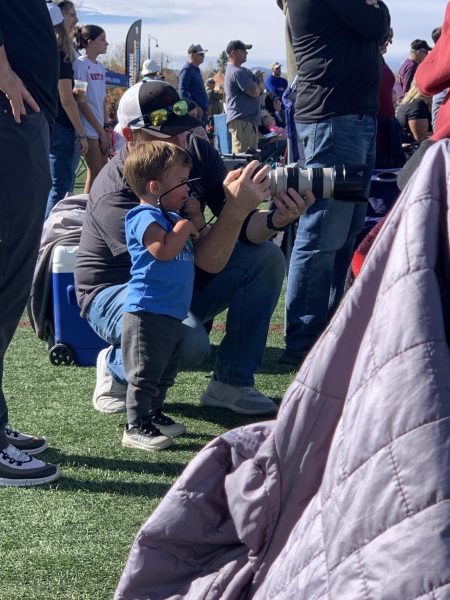 Stan Arnett takes pictures at a lacrosse tournament and has a budding photographer look on.