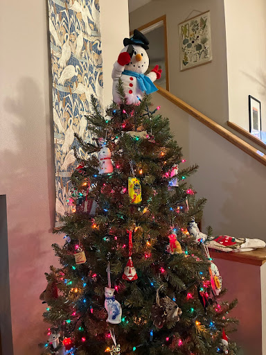 Selfie Snowman sits on his throne on the top of the Christmas tree.