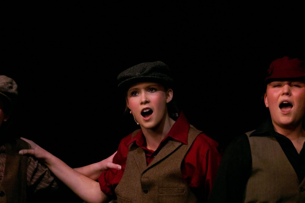 Junior Kirsten Thomason sings with the other newspaper delivery boys. 